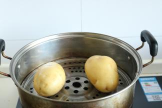 洗净的2个土豆放入蒸锅里。大火烧开，蒸10分钟左右，至土豆七八成熟即可。