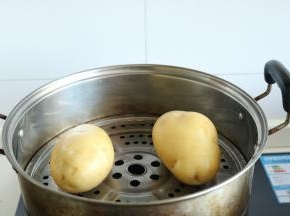 洗净的2个土豆放入蒸锅里。大火烧开，蒸10分钟左右，至土豆七八成熟即可。