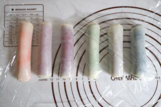 收口朝下，然后其余颜色也一样擀长卷起，盖上保鲜膜松弛十分钟