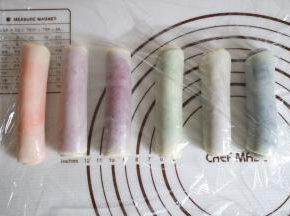 收口朝下，然后其余颜色也一样擀长卷起，盖上保鲜膜松弛十分钟