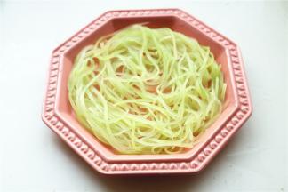 沥干一下水分，把青笋丝铺在盘子底部。