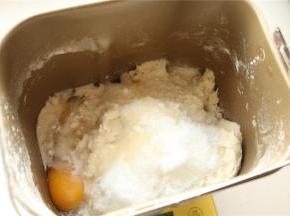 加入除了黄油和芝麻之外的主面团材料到面包机里，开启面包机揉一个面团程序，我的机子是15分钟，面包机揉面的时候炒香黑芝麻，2分钟左右就行，能听到噼里啪啦的声音时候关火，继续搅拌至冷却至室温。
