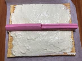 蛋糕卷凉透后，抹上冷藏好的白色淡奶油，这么糙不是打过了，是加了吉利丁的缘故，比较稠，所以看上去糙，实际这样是非常好卷的，黑色点点是香草精里的香草籽，铺好两种花纹的慕斯条。