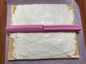 蛋糕卷凉透后，抹上冷藏好的白色淡奶油，这么糙不是打过了，是加了吉利丁的缘故，比较稠，所以看上去糙，实际这样是非常好卷的，黑色点点是香草精里的香草籽，铺好两种花纹的慕斯条。