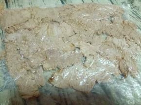 装入食品袋，用擀面杖来回擀，把煮熟的肉擀扁。如图