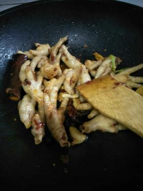 然后开中火，放入已经沥干的鸡爪，不停翻炒，炒至表面有点深色