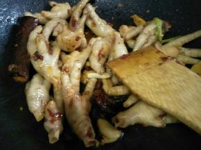 然后开中火，放入已经沥干的鸡爪，不停翻炒，炒至表面有点深色