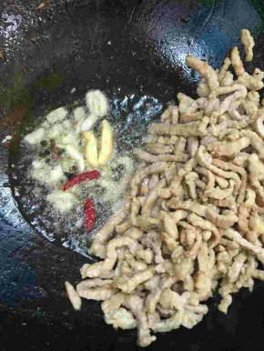 把肉丝拨到一边，放入生姜，蒜瓣，花椒，干辣椒爆香！
