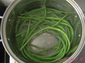 煮锅里水热后，滴入两滴食用油，放入洗净的豇豆焯烫一下；