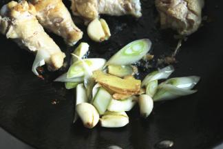 把鸡翅根拨到一边，放入葱姜蒜炒出香味。