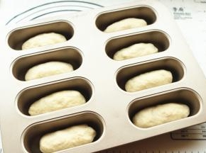 每一份小面团搓圆搓长，放进学厨小热狗模具内。送入烤箱发酵档开始二次发酵，总共可以烤两盘。