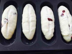 二发后，在面包中间割一道口子，建议割两次，但不要太深，否则会漏出奶酪馅料，遇到蔓越莓挡路，不要硬割，你割不断它滴，让开它，或者扣下来……