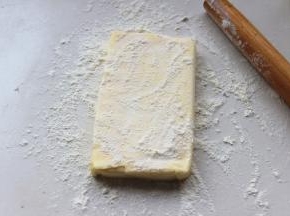 等待面团的时候，开始处理黄油，刚从冷藏室里拿出来的黄油非常硬，但不要担心，就像有些人一样，黄油也是非常欠揍的。案板上撒点粉，黄油上也撒一些，用擀面杖开始敲打黄油，一会就会变得非常软，就可以擀到需要的大小了。一定要多撒粉，不然黄油就会在敲打的时候粘到案板上。