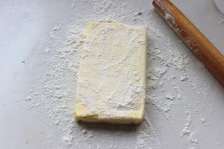 等待面团的时候，开始处理黄油，刚从冷藏室里拿出来的黄油非常硬，但不要担心，就像有些人一样，黄油也是非常欠揍的。案板上撒点粉，黄油上也撒一些，用擀面杖开始敲打黄油，一会就会变得非常软，就可以擀到需要的大小了。一定要多撒粉，不然黄油就会在敲打的时候粘到案板上。