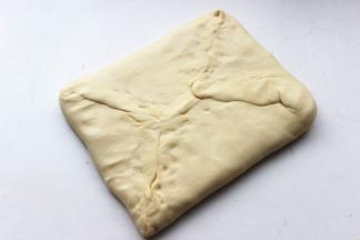 冻好的面团拿出来，擀成黄油块大小的两倍大，把黄油片包在里面。四周捏紧，紧紧包住黄油。