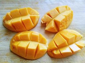 芒果洗干净后从中间切开，再果肉上划刀，如图。