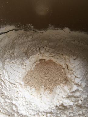 随后加入面粉，在面粉中挖一个洞加入酵母。