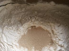 随后加入面粉，在面粉中挖一个洞加入酵母。