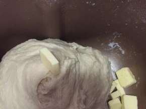 面团揉至光滑，能拉出大片薄膜时加入黄油。
