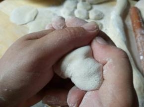 开始包饺子，饺子皮中间放馅，两手这样握住，轻轻一使劲，把饺子皮粘在一起即可