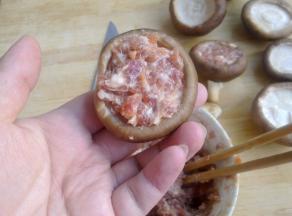 把肉馅填进香菇的伞盖里。