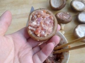 把肉馅填进香菇的伞盖里。