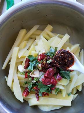 冰好的土豆装入盆中，倒入包好酱汁，在加入一勺辣椒油