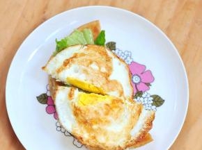 将一半飞饼皮垫底，铺上生菜、一切为二的煎蛋。