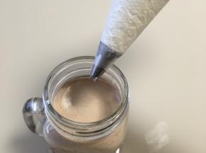 做好的摩卡咖啡倒入自己喜欢的杯子内，裱上一层奶油，从外往里漩涡裱上
