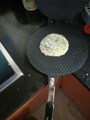 将烧热的模具上舀上一汤勺面糊，盖上盖子，在煤气灶上烧一会儿，有点上色了就反面。