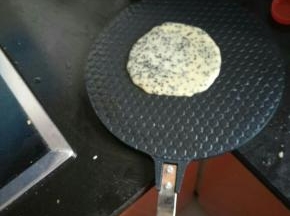 将烧热的模具上舀上一汤勺面糊，盖上盖子，在煤气灶上烧一会儿，有点上色了就反面。