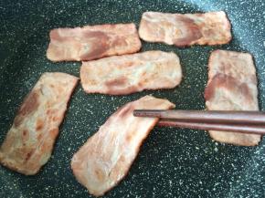 培根放入锅中煎熟。