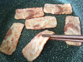培根放入锅中煎熟。