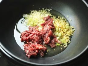 下入葱姜蒜末和牛肉末。
