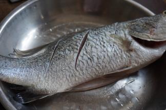 鲈鱼去鳞去内脏，洗净，在两侧鱼身上斜切三刀