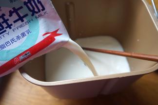 将剩下的两袋牛奶倒入桶中，利用牛奶入桶的冲击力，可以将菌粉均匀地融化；再用干净无油的勺子搅拌，以使酸奶菌溶解得更彻底