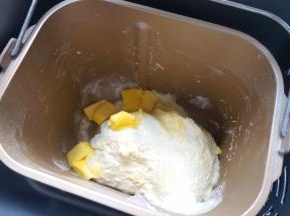 一个揉面程序后，面团有些筋度了，将软化的黄油入桶中，继续完成剩下的揉面程序