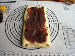 两边空白面皮向中间对折，在最上面再铺抹一层红豆沙