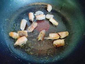 不粘锅中加入适量食用油，油温8成时加入腌制好的虾头煸炒。