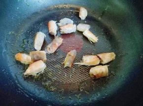 不粘锅中加入适量食用油，油温8成时加入腌制好的虾头煸炒。