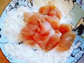 把腌制好的鸡块放在面粉容器中，使其沾满面粉。