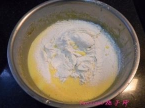 将低筋面粉和泡打粉混合后筛入蛋黄里，用橡皮刮刀翻拌均匀，成为蛋黄面糊。