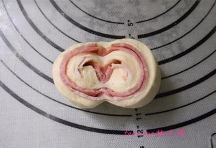 用刀在卷好的面包胚中间切开（不要切断），将切开的两边向下翻，码放在烤盘里，包好保鲜袋，进行二次醒发1小时；