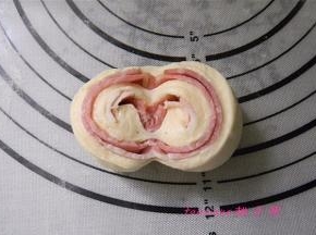 用刀在卷好的面包胚中间切开（不要切断），将切开的两边向下翻，码放在烤盘里，包好保鲜袋，进行二次醒发1小时；