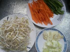 豆芽菜清洗干净，青椒切成丝，红萝卜切丝，葱切碎，蒜切片。