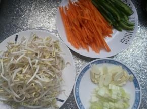 豆芽菜清洗干净，青椒切成丝，红萝卜切丝，葱切碎，蒜切片。