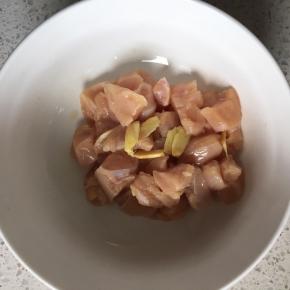 鸡胸肉洗净沥干水，切块倒入碗中，加入切片的姜片，倒入一瓶盖料酒