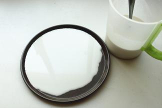 找一个不沾的平盘，我用了披萨盘，舀入适量面糊，转动盘子使面糊铺满盘子。