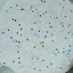 取一烤盘，铺上油纸，把酸奶倒入盘中，用刮刀搅拌，刮平，撒上熟黑白芝麻，放入冰箱冷冻室，冷冻3小时以上即可。