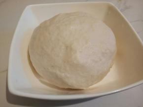 然后再加入一勺食用油，这样做好的饼皮更加脆，再用手把面粉揉成团，盖保鲜膜醒发半小时以上，